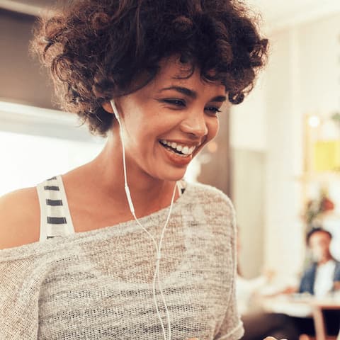 Smiling medium-skinned woman with earphones smiling