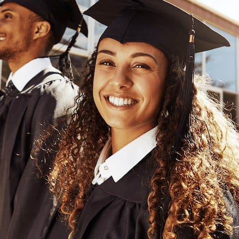 Smiling medium-skinned young woman wearing a graduation cap